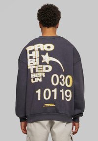 Sudadera de gran tamaño de color gris oscuro con texto texturizado y brillante en blanco y dorado: "PROHIBIDO BERLÍN 030 10119" y un motivo de estrella. Puños acanalados.