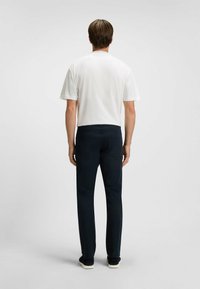 Witte t-shirt met korte mouwen en marineblauwe broek, met een slim fit ontwerp, een gladde textuur en geen zichtbare patronen of logo's.