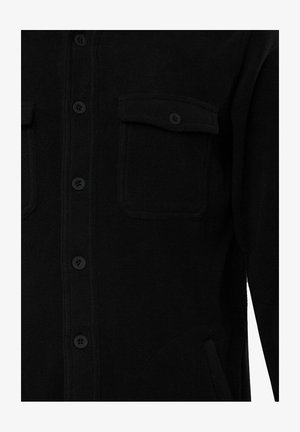 Camisa de forro negro con cierre de botones en la parte delantera, dos bolsillos en el pecho y una textura suave. Los botones también son negros para un aspecto uniforme.