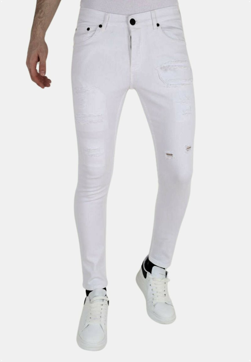 Witte skinny jeans met gescheurde details, voorzien van scheuren en rafelige accenten. Gecombineerd met witte sneakers en een aansluitend topje.