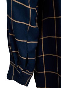 Navy shirt sleeve with a grid pattern of thin gold lines. Features a buttoned cuff and side vent openings for ease of movement.