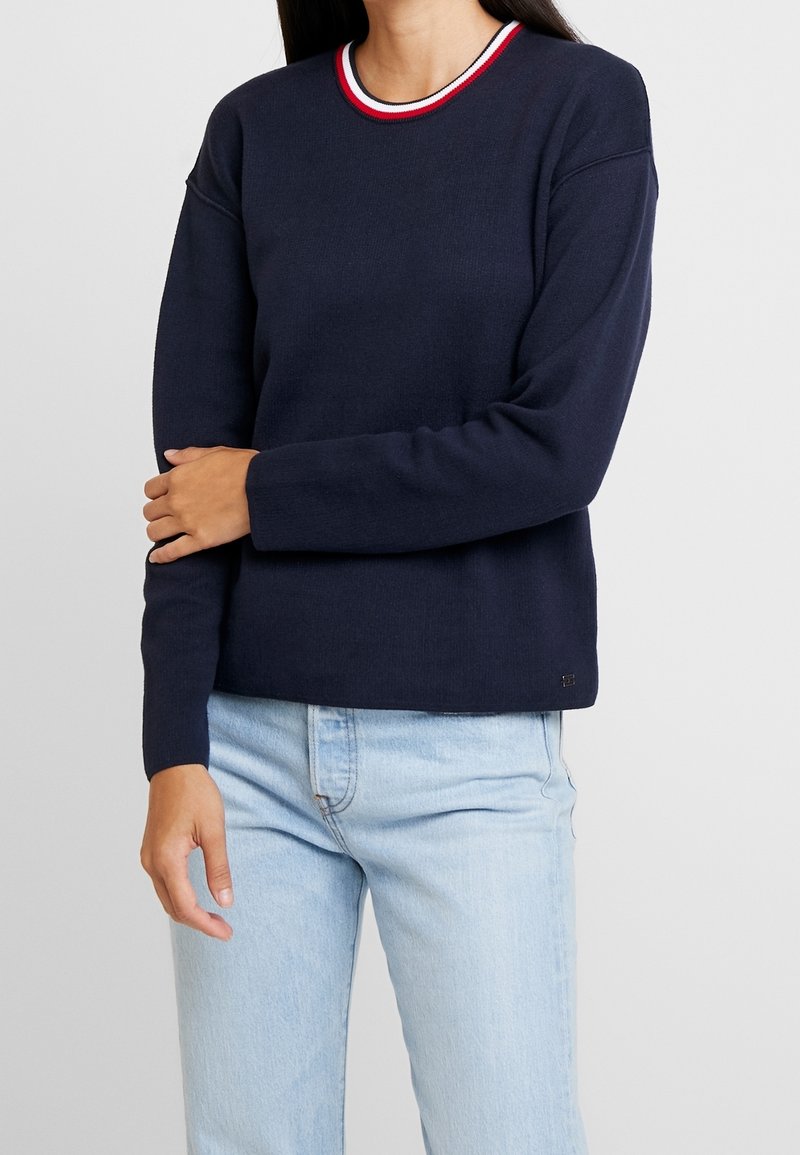 Pull-over bleu marine avec un col rond orné d'une bordure rayée tricolore. Confectionné en tissu texturé, manches longues et coupe décontractée.