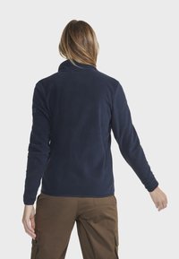 Pull en polaire bleu marine avec un col haut et des manches longues, présentant une texture lisse et une coupe ajustée.