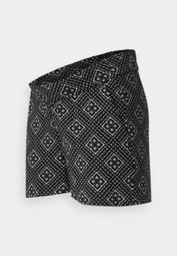 Černé kraťasy s geometrickým vzorem a bílými akcenty. Vyrobené z lehkého materiálu; pas má přehnutý okraj pro stylový vzhled.