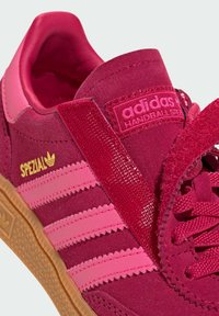 Adidas Spezial sneakers i mørk rosa semsket skinn med lyse rosa striper. Har teksturert tunge, gummisåle og detaljer med gullmerke.