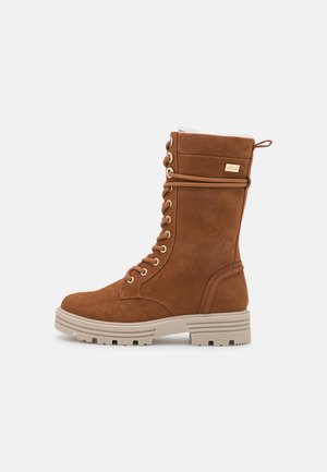 Tan faux suede lace-up boots with a round toe, padded collar, gold hardware, and a chunky beige rubber sole.