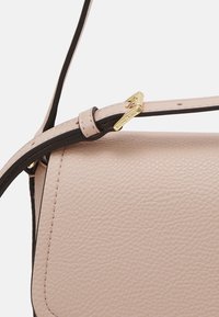 Borsa in pelle beige con tracolla regolabile e fibbia dorata impressa con il nome del marchio.