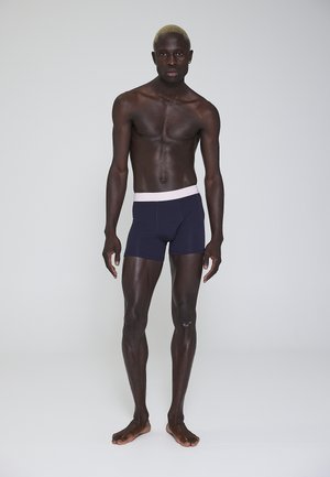 Marineblå boxershorts med en lyserød talje, lavet af blødt stof, der har et tætsiddende design og en sømløs finish.