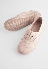 Lyserøde canvas slip-on sko med små guld sommerfuglemønstre, metaløjer og en tekstureret gummisål med bølgende design.