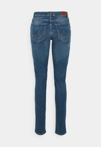 Jeans skinny de denim azul com uma cintura de altura média, apresentando dois bolsos traseiros e costura em contraste. O tecido tem uma textura clássica e suave.