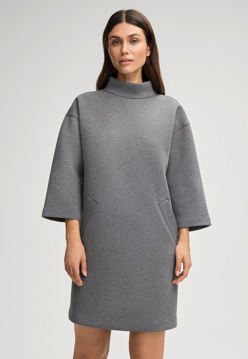 Grijze sweatshirtjurk met een hoge kraag, brede mouwen, twee zijzakken en een zachte textuur. Halverwege de dijen lengte.