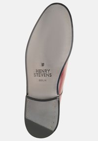 Leren schoenzool met een gladde, grijsglanzende afwerking, met gegraveerde tekst "HENRY STEVENS BERLIN" en messingkleurige nagels in de buurt van de hak.