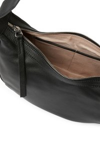 Svart läderhandväska med strukturerad yta, med en ovandel som stänger med dragkedja och en beige inredning med ett subtilt mönster.