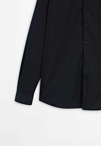 Czarna koszula z długim rękawem z zapięciem na guziki, wykonana z gładkiego materiału. Posiada zaokrąglony kołnierz i podwójne mankiety. Minimalistyczny design, bez wzorów.
