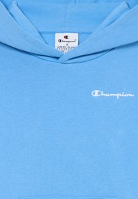 Sweat-shirt à capuche bleu clair en mélange de coton. Doté d'une poche avant et d'un logo "Champion" brodé en blanc sur la poitrine.