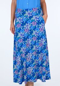 Maxi-Rock mit floralem Design in Blau und Lila, ausgestattet mit einer glatten Textur. Er verfügt über einen breiten Taillenbund und seitliche Taschen.