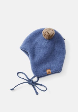 Blue woolen baby hat with brown pom-pom on top and tied strings at the chin, laid flat on a white background.