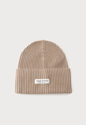 Bonnet beige en maille côtelée avec revers, comportant une étiquette blanche indiquant "Marc O'Polo" sur un fond clair uni.