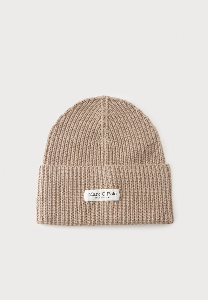 Bonnet beige en maille côtelée avec revers, comportant une étiquette blanche indiquant "Marc O'Polo" sur un fond clair uni.