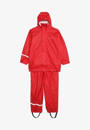 Červený nepromokavý dešťový oblek se kapucí, patentními uzávěry, reflexními bílými akcenty, elastickými manžetami a kalhotami se stahovací šňůrou a popruhy na nohy.