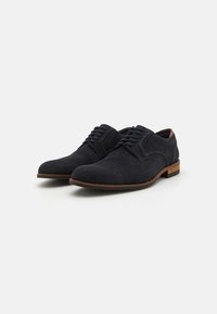 Scarpe stringate in suede blu navy con punta arrotondata e tacco in legno basso; presentano una texture liscia e un design minimalista.