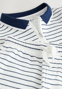 Stribet polo-krave beklædningsgenstand i hvid og navyblå; har lynlås og justerbar snor i taljen; bomuldsblanding tekstur.