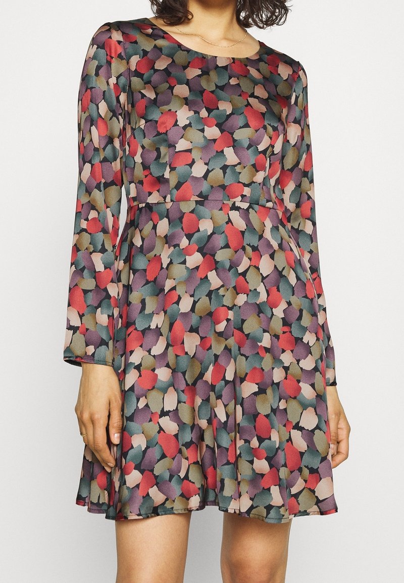 Robe à manches longues en tissu transparent, avec un motif de feuilles colorées dans des teintes de rouge, vert et violet. Conception de jupe évasée.