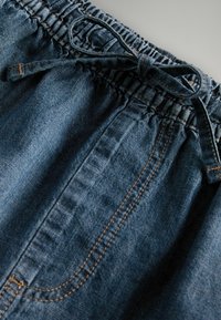 Mørkeblå denimshorts med elastisk talje, der har snøre og kontrastfarvet orange syninger langs sidesømmene.