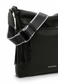 Black textured leather crossbody bag with a silver accent. Features a detachable strap with a fringe detail and a zippered pocket.