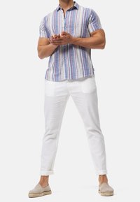 Short-sleeve striped shirt in blue, red, and white; lightweight fabric. Paired with white pants and beige espadrilles.