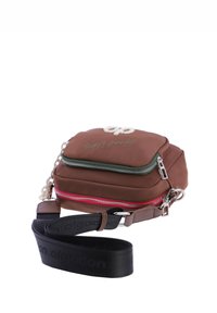 Bolso bandolera marrón hecho de material suave, con cremalleras verde y roja, detalle de cadena y una correa negra ajustable con logo.