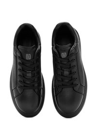 Zapatillas de cuero negro con puntera redonda, cordones en la parte delantera y perforaciones en los laterales; textura suave y logo sutil en la lengüeta.