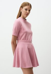 Abito rosa con collo alto, maniche corte e gonna svasata. Realizzato in tessuto morbido, presenta una vita aderente e un design senza cuciture.