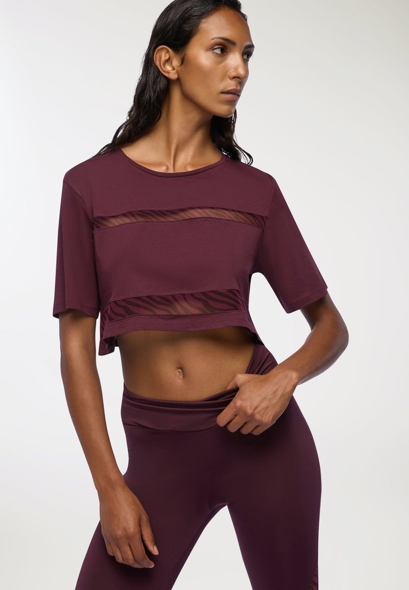 Burgundowa sportowa bluzka na krótki rękaw, z krótkim fasonem, z przezroczystymi siateczkowymi panelami oraz poziomymi paskami w okolicy talii.