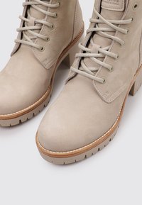 Beige Knöchelstiefel aus glattem Leder, mit runder Zehenpartie, Schnürdesign, strukturiertem Obermaterial und einer klobigen, geriffelten Sohle.