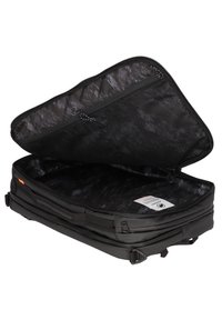 Svart rektangulär mjuk resväska med dragkedja och nätficka inuti, visar en inre skötseletikett.