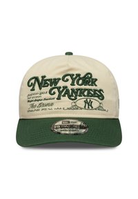 Μπεζ καπέλο με πράσινο γείσο, με κεντητό κείμενο "New York Yankees" και λογότυπα μπροστά· ρυθμιζόμενο λουράκι στο πίσω μέρος.