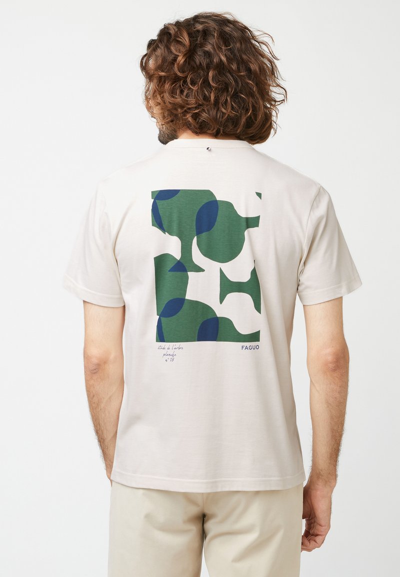 Beige Baumwoll-T-Shirt mit einem grünen und marineblauen abstrakten Muster auf der Rückseite, mit bedrucktem Text und Logo am unteren Ende. Kurze Ärmel.