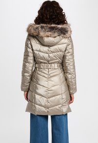 Dikke, knielange beige parka met een bontomrand capuchon, een ceintuur in de taille, chevrons quilten en een glanzende afwerking.