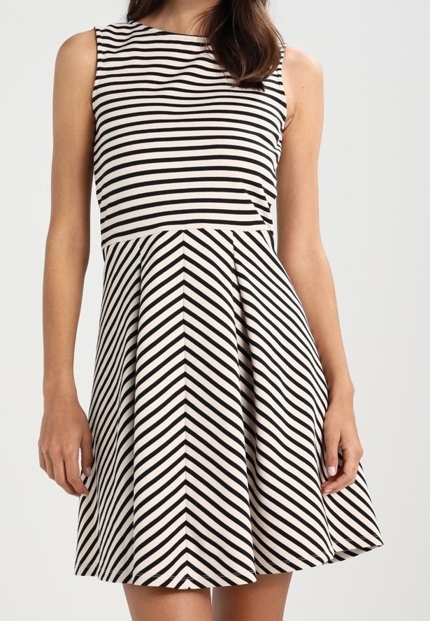 Robe sans manches rayée noir et blanc avec des rayures horizontales sur le corsage et des rayures diagonales formant un motif en chevrons sur la jupe.