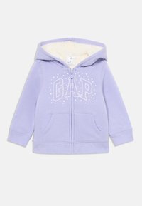 Felpa con zip per bambini di colore lilla, con fodera in pile bianco, tasche anteriori e un motivo a stelle bianche che forma la parola "GAP" sul petto.
