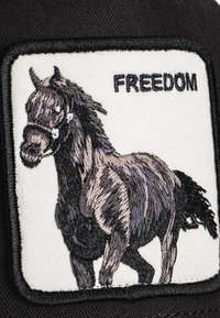 Black cap featuring an embroidered patch with a horse illustration in shades of brown and gray, accompanied by the text “FREEDOM” in black.