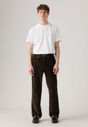 Witte T-shirt met korte mouwen gecombineerd met donkergroene ribstof broek, met een rechte pijpdesign en zichtbare stiksels op de zakken.