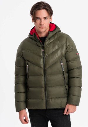 Chaqueta acolchada verde oliva con capucha roja, bolsillos con cremalleras y un patrón de rombos, hecha de material brillante y ligero.