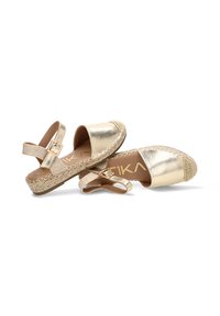 Par de sandalias espadrilles de color oro metálico con correas en el tobillo y suelas de yute trenzado sobre fondo blanco.