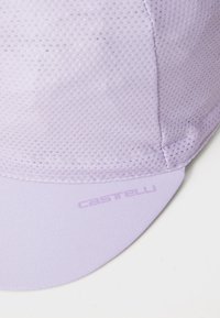 Világoslila hálós kerékpáros sapka ívelt ernyővel és relief „Castelli” logóval. Sima, lélegző textúrája van, és varrott varratokkal rendelkezik.