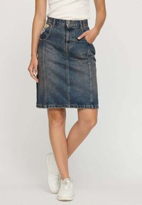 Jupe en denim à coupe droite, mi-longue, de couleur bleu délavé. Présente des poches avant, une fermeture par bouton et des coutures blanches le long de l'ourlet.