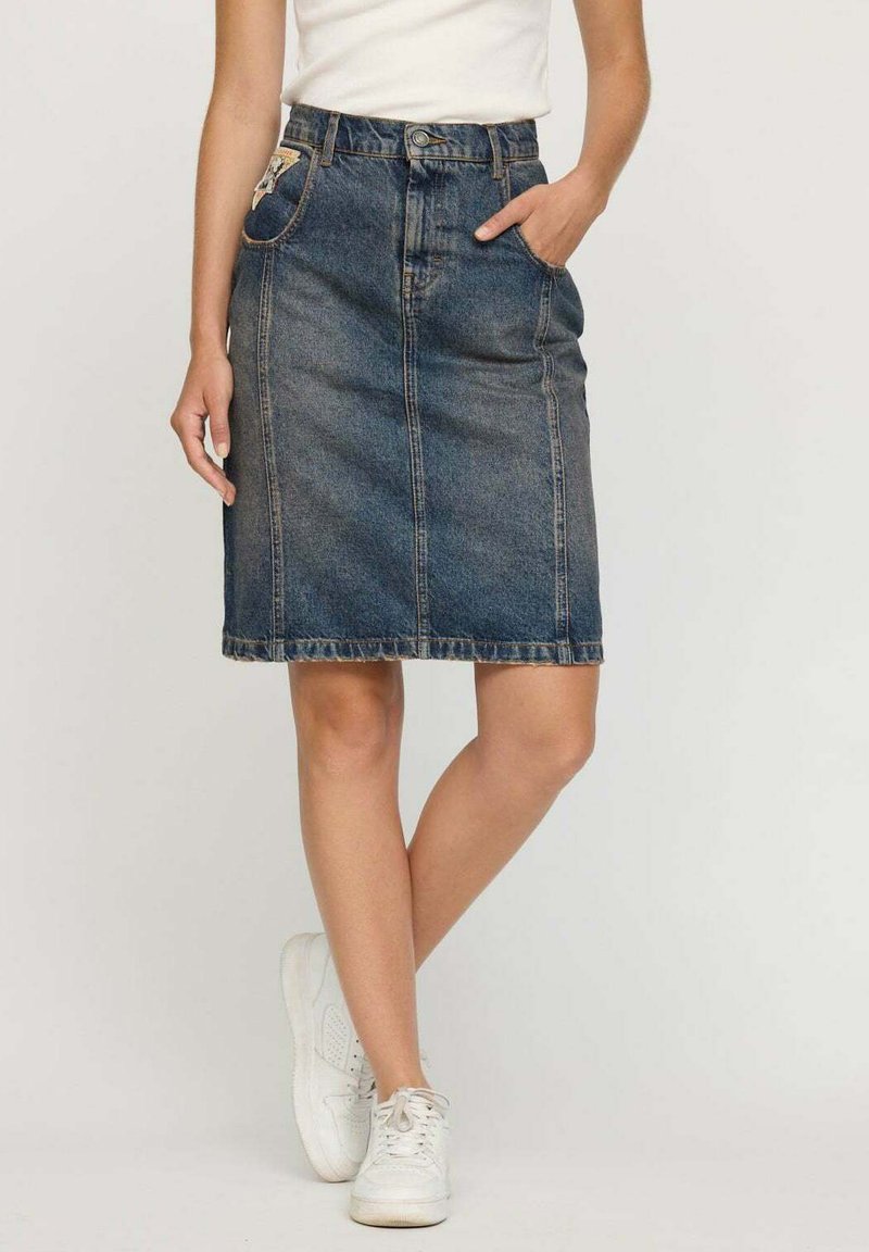 Jupe en denim à coupe droite, mi-longue, de couleur bleu délavé. Présente des poches avant, une fermeture par bouton et des coutures blanches le long de l'ourlet.