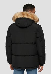 Sort dunjakke med aftagelig hætte i tan-imitationspels, quiltet tekstur og elastiske manchetter. Har en afslappet pasform og et minimalistisk design.