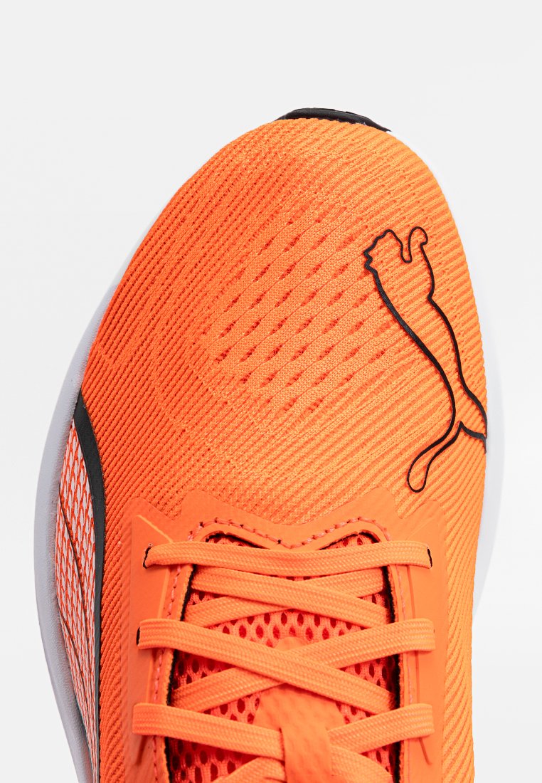 Scarpa da ginnastica di un vivace arancione con upper in tessuto testurizzato. Presenta un logo nero e sezioni in rete, con lacci piatti e suola bianca.